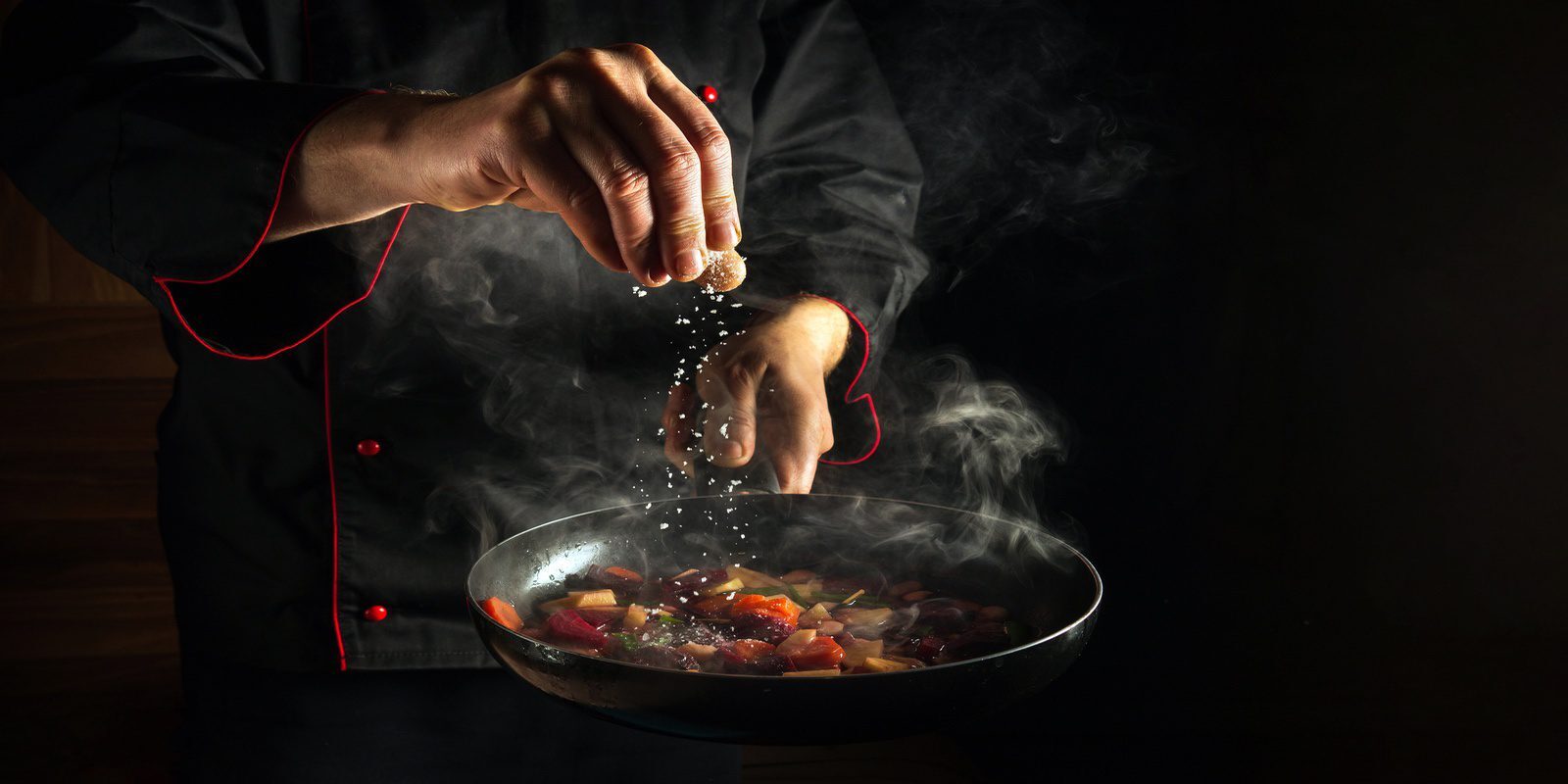 Chef seasoning vegetables being cooked